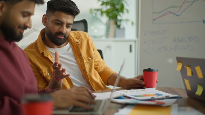 Two colleagues reviewing charts and a business plan at a desk