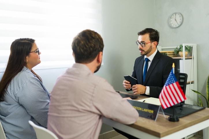A couple reviews documents with an adviser at a desk
