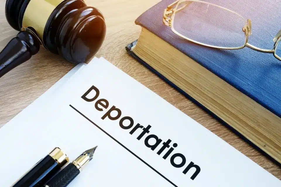 Document labeled Deportation beside law books, glasses and a gavel